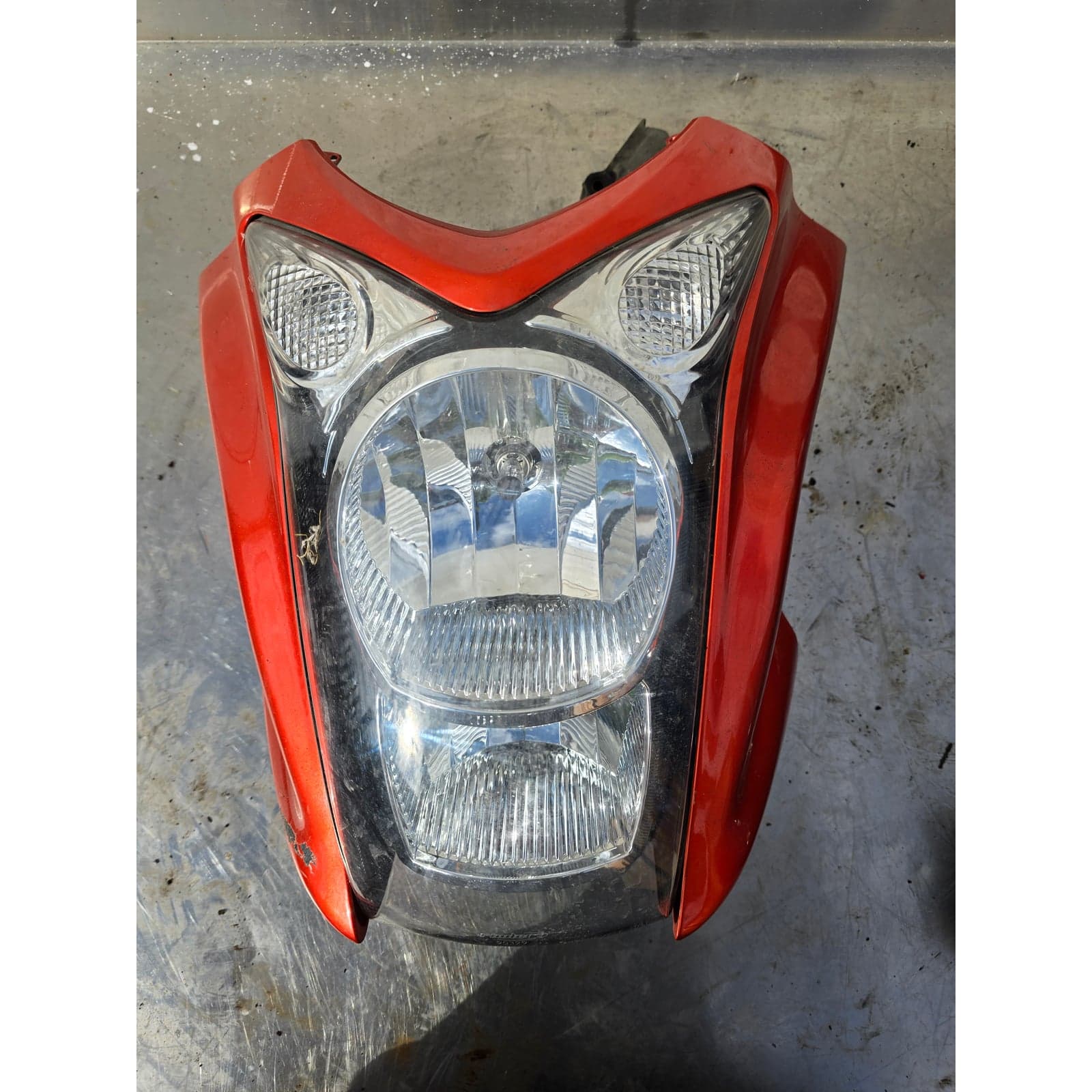 Front view of Kawasaki ER-6n headlight assembly with clear lens and orange fairing.