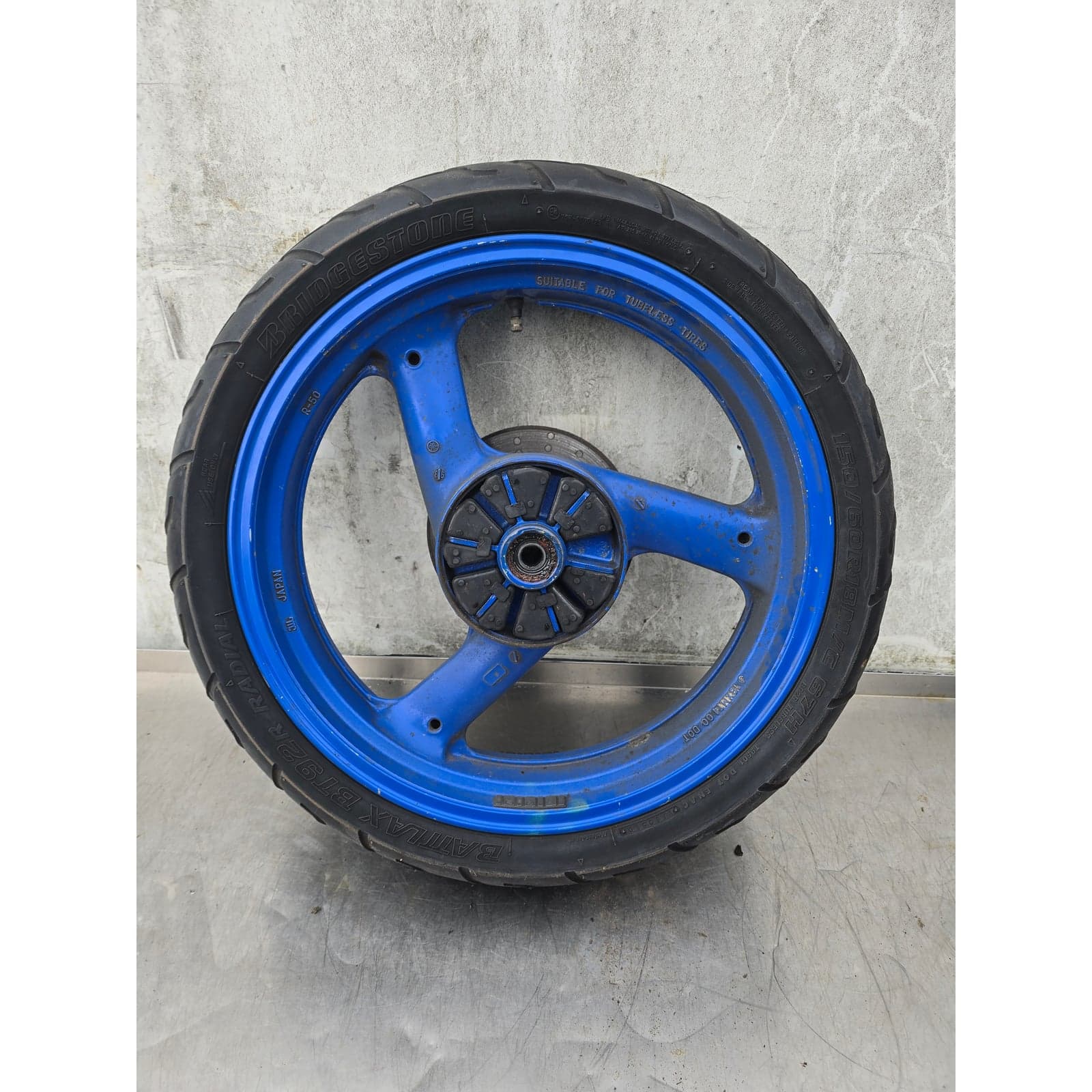 Complete rear wheel assembly featuring a blue 3-spoke rim with mounted tyre and brake disc